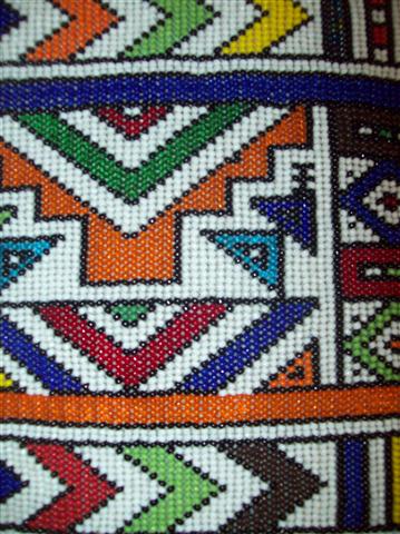 detalle de la vestimenta de  muñeca tradicional de la etnia Ndebele, realizada con fieltro, lana y decorada con cuentas de vidrio y plástico
