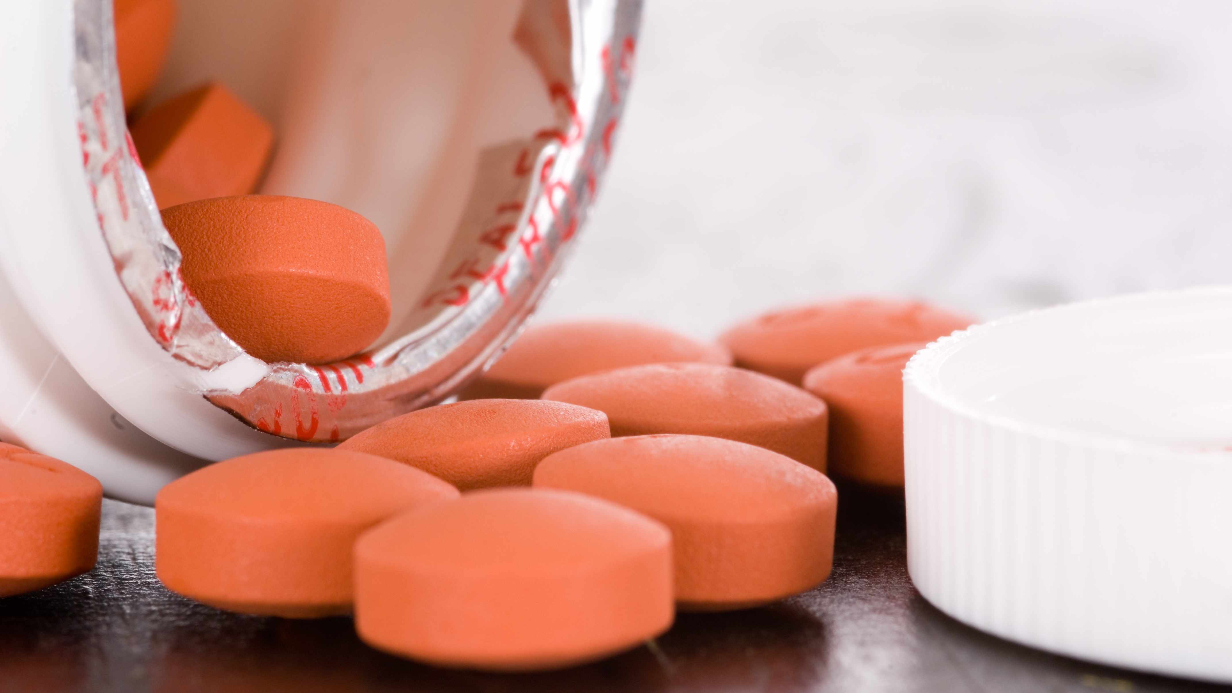an-open-medication-container-spilling-ibuprofen-tablets-out-onto-a-table-16X9