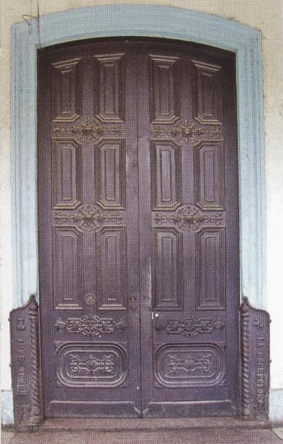 Puerta principal y guardacantones con la fecha de 1882