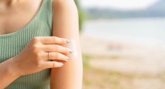 close up front view of woman applying sunscreen lotion to skin at beach in holiday for protect about sunlight , healthy lifestyle and summer season concept