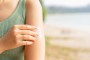 close up front view of woman applying sunscreen lotion to skin at beach in holiday for protect about sunlight , healthy lifestyle and summer season concept