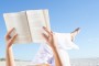 Mixed race woman reading book on beach